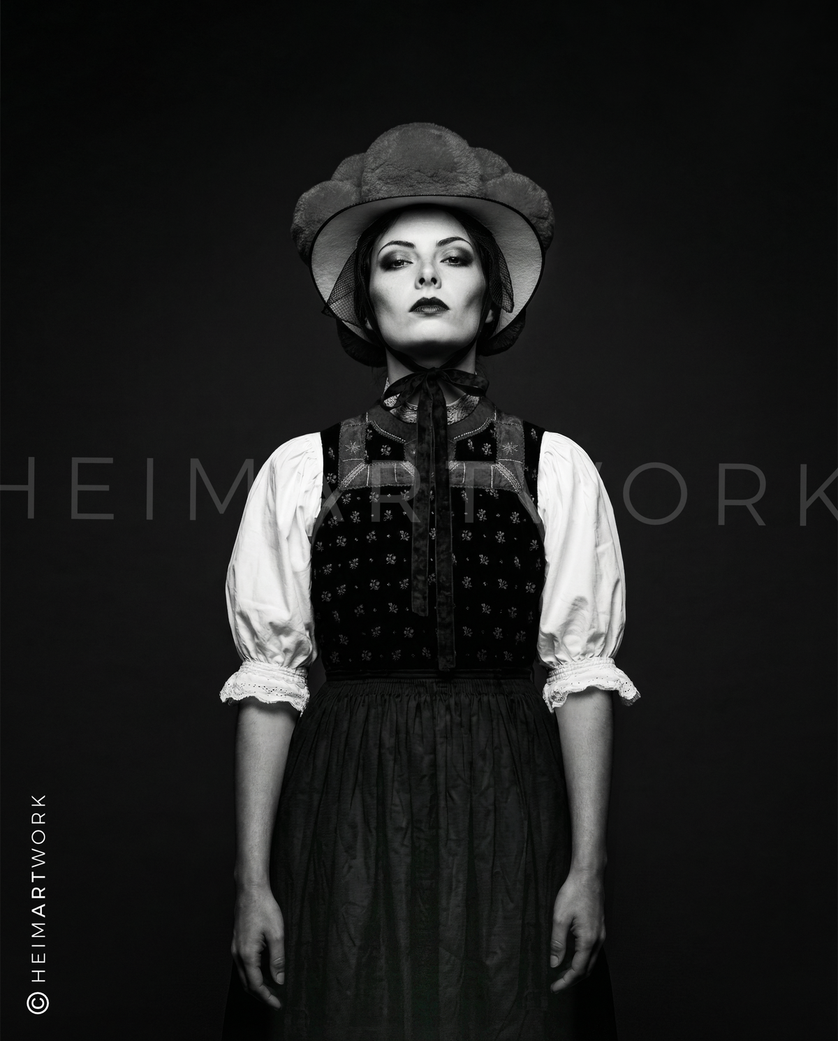 Künstlerische Schwarz-Weiß-Fotografie einer Schwarzwälderin in traditionellem Mieder und Bollenhut. Diese Schwarzwald Leinwand fängt die feinen Details der Stickerei und den entschlossenen Blick der Porträtierten in edler Monochrom-Optik ein.