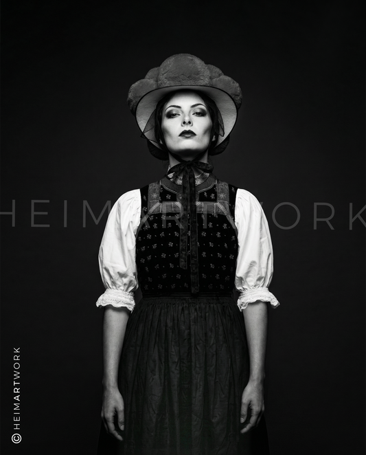 Künstlerische Schwarz-Weiß-Fotografie einer Schwarzwälderin in traditionellem Mieder und Bollenhut. Diese Schwarzwald Leinwand fängt die feinen Details der Stickerei und den entschlossenen Blick der Porträtierten in edler Monochrom-Optik ein.