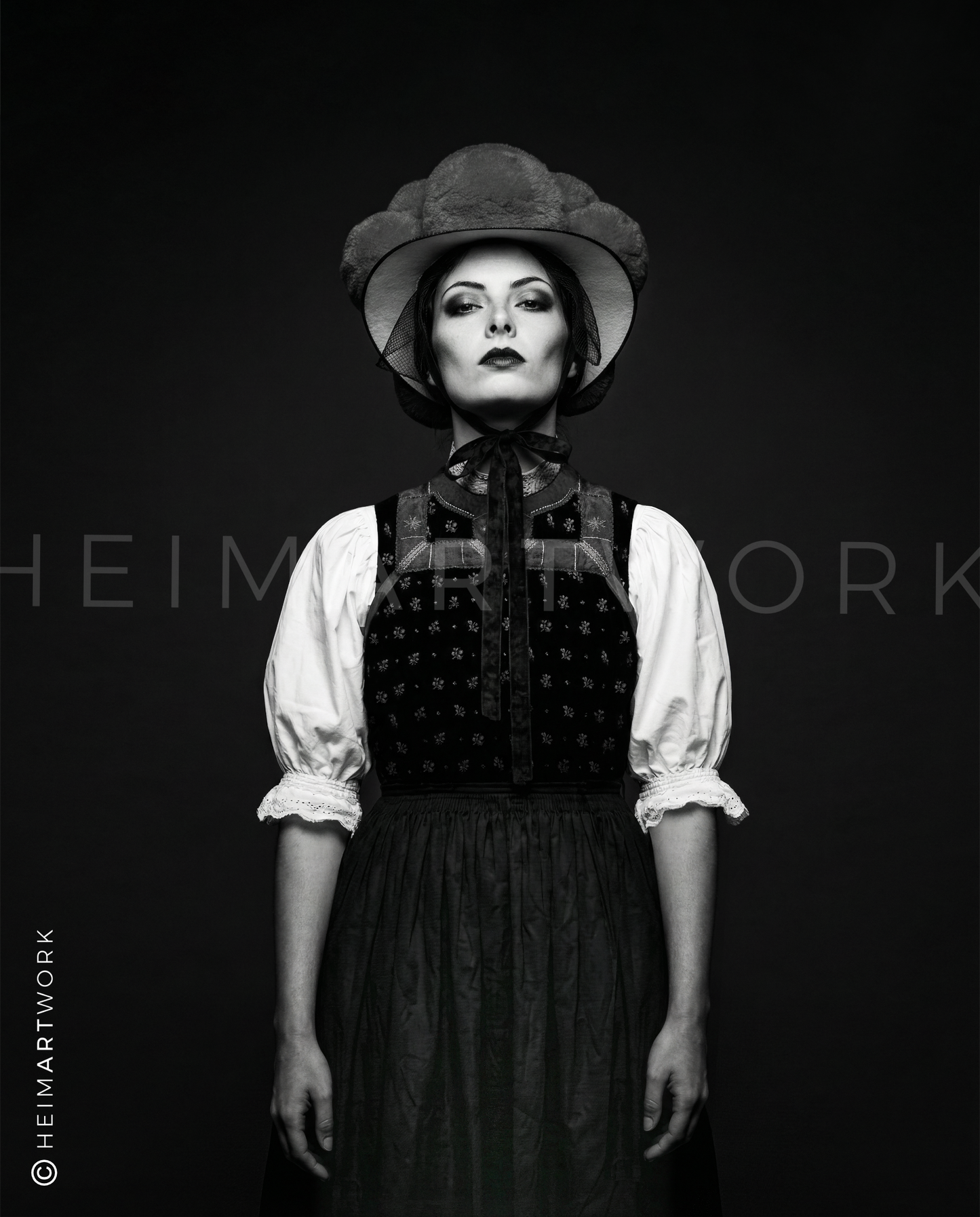 Künstlerische Schwarz-Weiß-Fotografie einer Schwarzwälderin in traditionellem Mieder und Bollenhut. Diese Schwarzwald Leinwand fängt die feinen Details der Stickerei und den entschlossenen Blick der Porträtierten in edler Monochrom-Optik ein.