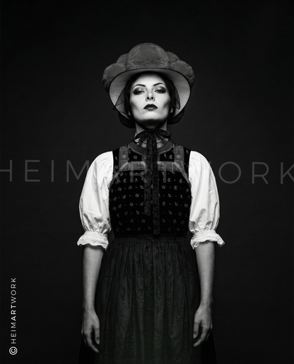 Künstlerische Schwarz-Weiß-Fotografie einer Schwarzwälderin in traditionellem Mieder und Bollenhut. Diese Schwarzwald Leinwand fängt die feinen Details der Stickerei und den entschlossenen Blick der Porträtierten in edler Monochrom-Optik ein.
