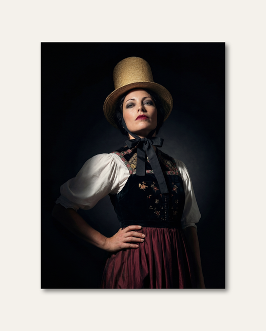 Elegantes Schwarzwald Wandbild mit stolzem Frauen-Porträt, feiner Stickerei und edlem Strohhut vor dunkler Kulisse.