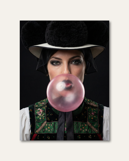 Eine Frau in klassischer Schwarzwälder Tracht mit schwarzem Bollenhut pustet eine große, rosa Kaugummiblase vor einem dunklen Studiohintergrund. Die humorvolle Kombination aus traditionellem Heimatmotiv und frecher Pop-Art-Ästhetik schafft ein modernes, ausdrucksstarkes Kunstwerk.