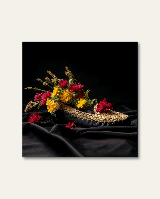Kunstvolles Schwarzwald Wandbild von HEIMARTWORK mit geflochtenem Strohschuh, farbenfrohen Blüten und edler Lichtstimmung auf dunklem Grund.