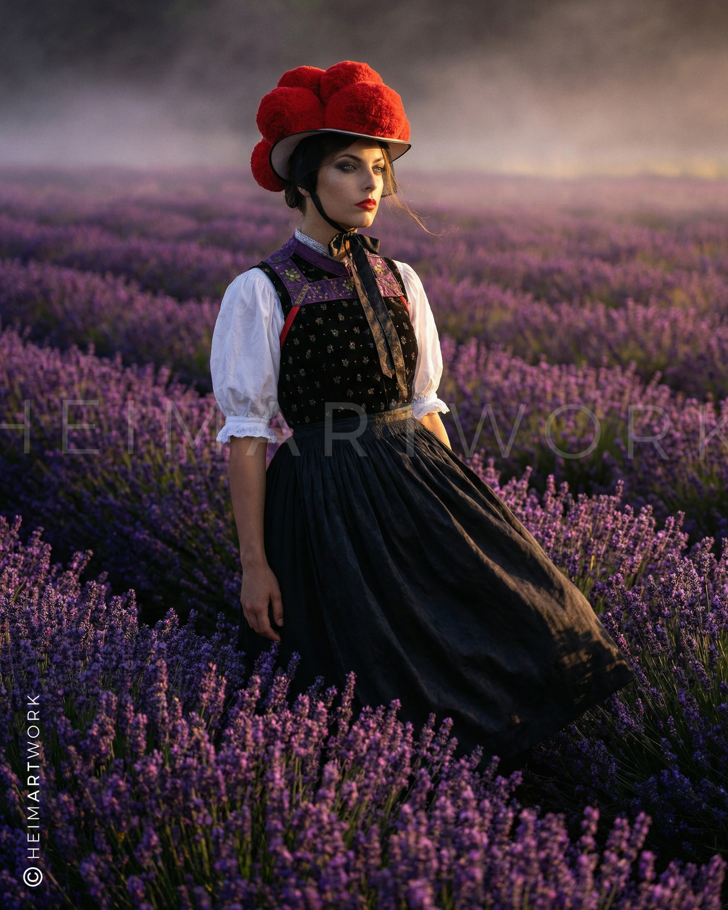 Romantisches Porträt einer Schwarzwälderin mit Bollenhut in einem weiten Lavendelfeld bei sanftem Abendlicht. Diese Schwarzwald Leinwand besticht durch das harmonische Zusammenspiel zwischen dem leuchtenden Rot des Hutes und den violetten Blüten.