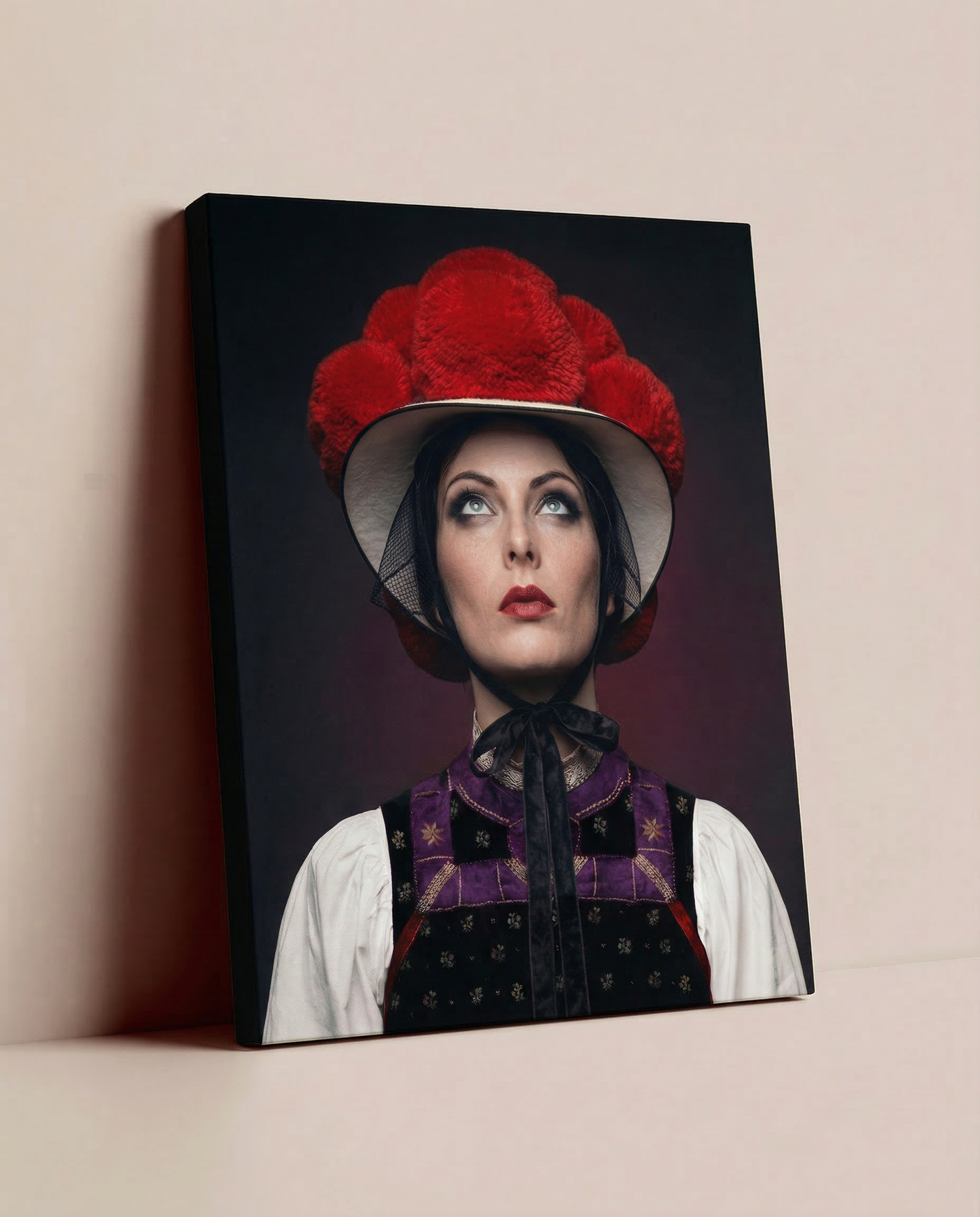 Ein fertig bespanntes Leinwandbild mit dem Schwarzwald-Bollenhut-Motiv, das lässig auf dem Boden an einer einfarbigen, beige-gestrichenen Wand lehnt.